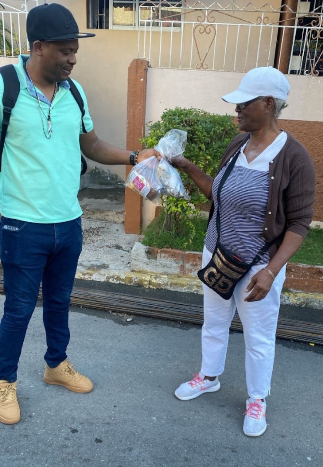 A volunteer giving Easter bun and cheese to a woman in Jamaica
