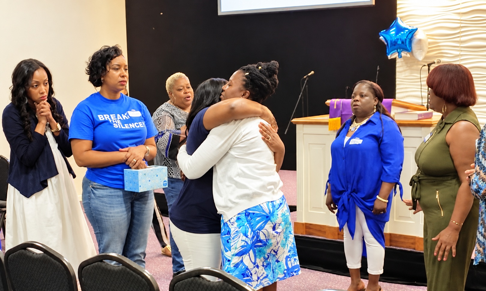 Women sharing a supportive embrace at the 2019 Naples Break the Silence Conference